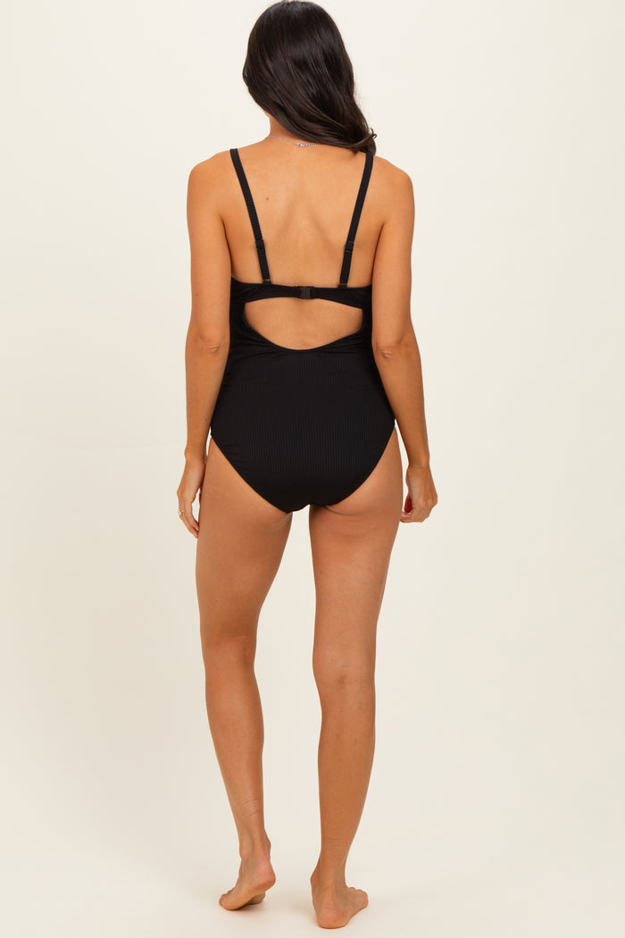 woman wearing a black ribbed one-piece swimsuit with a cut-out back detail