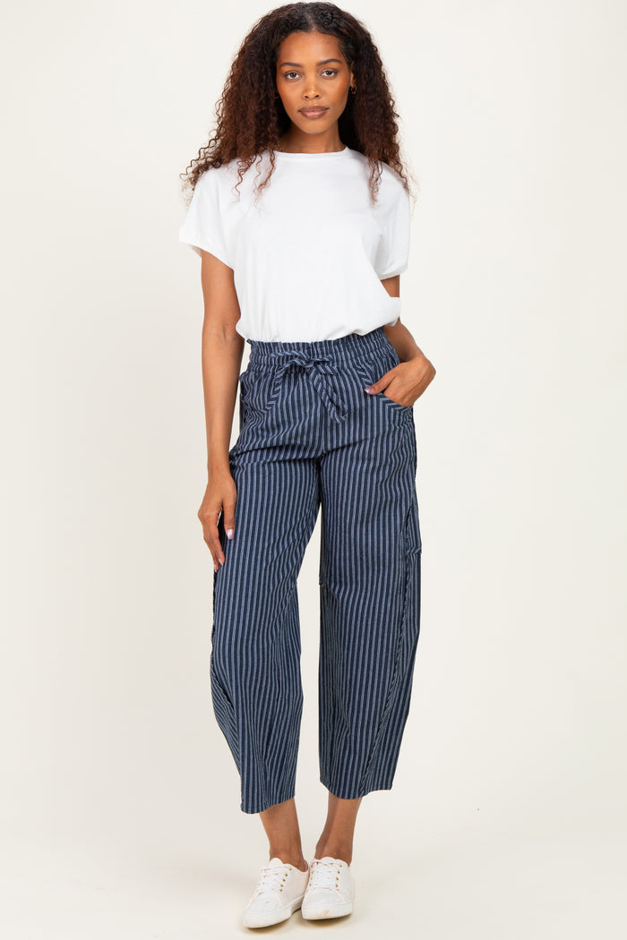 woman wearing a white short sleeve t-shirt and navy blue striped paperbag pants