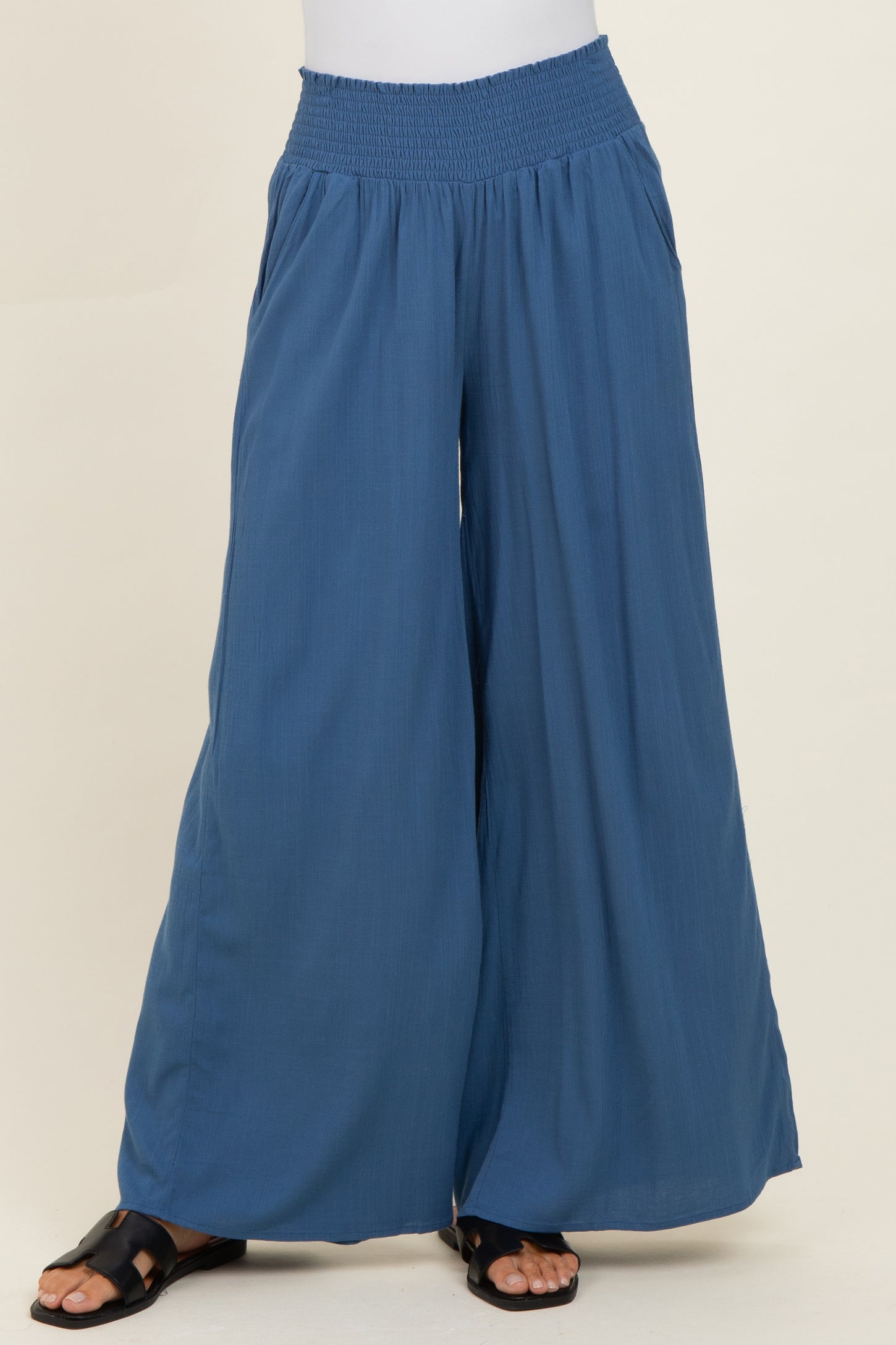 woman wearing blue wide-leg pants with a smocked waistband and a flowy silhouette