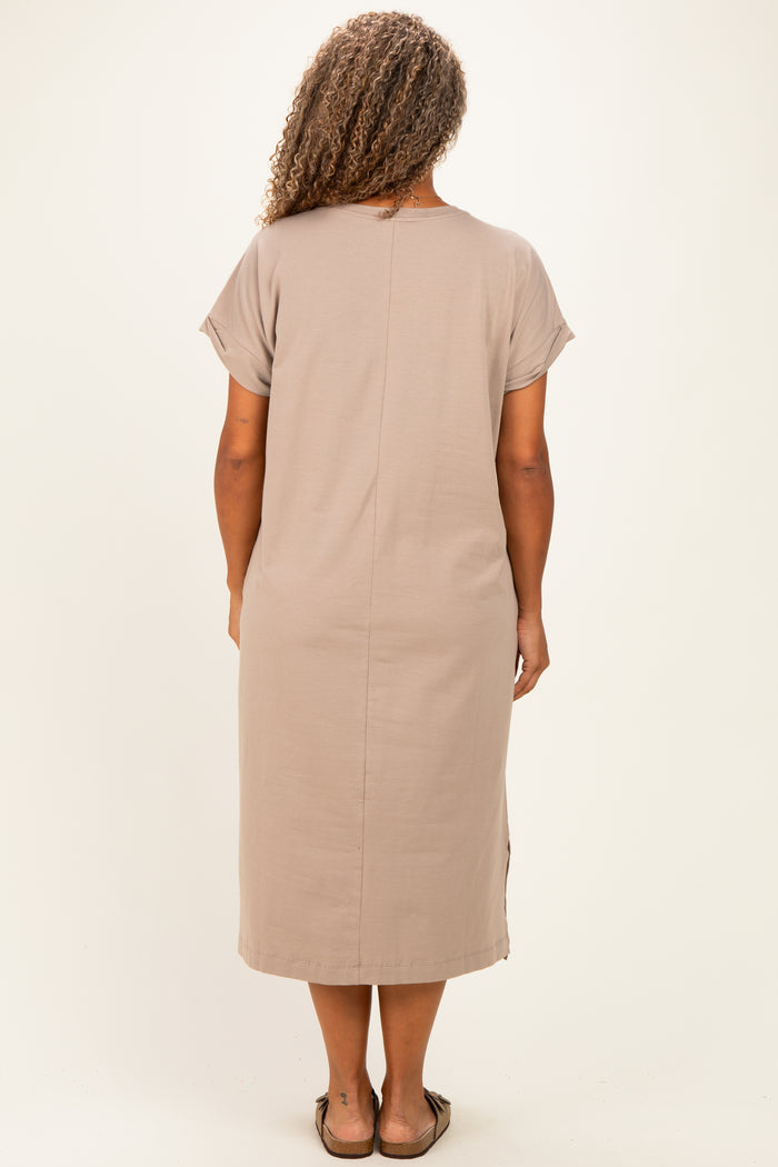 woman wearing a taupe short sleeve plus-size dress with a straight cut and side slits, viewed from the back