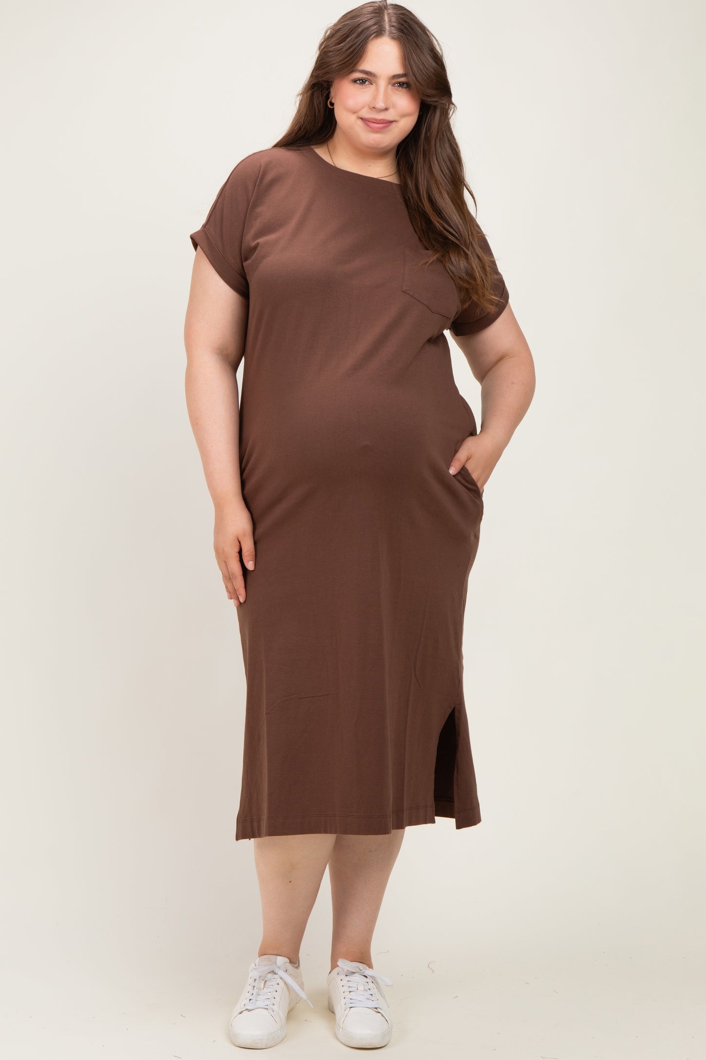 woman wearing a brown short sleeve maternity dress with pockets and a side slit, showing her baby bump