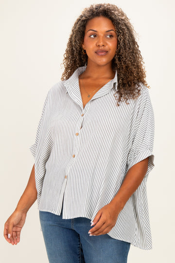 woman wearing a striped button-up blouse with a relaxed fit and rolled sleeves, paired with blue jeans