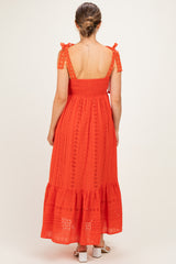 woman wearing a red maternity dress with a smocked bodice, tie shoulder straps, and a tiered skirt
