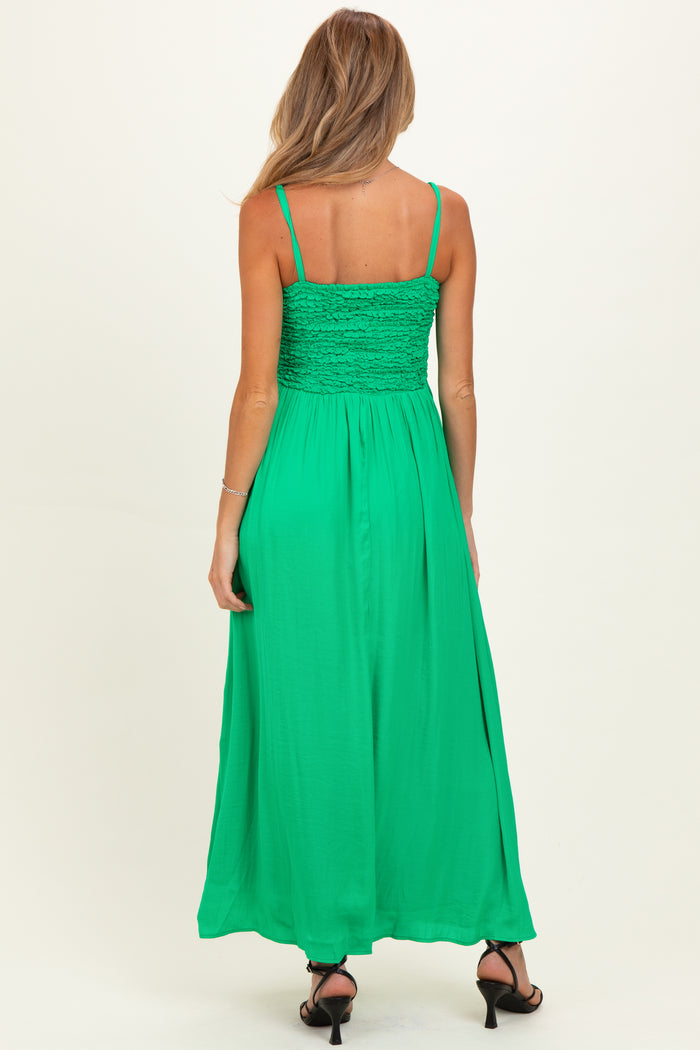 woman wearing a green maternity maxi dress with smocked bodice and spaghetti straps, showing a baby bump from the back