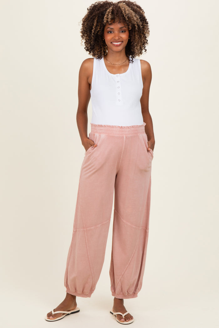 woman wearing a white maternity tank top and pink maternity lounge pants with pockets