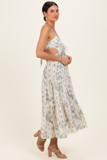 woman wearing a white floral print maxi dress with adjustable shoulder straps and a tiered hemline