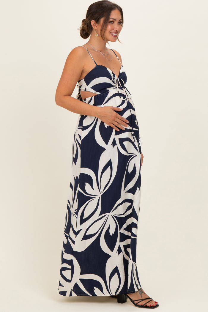woman wearing a navy and white floral print maternity maxi dress, cradling her baby bump
