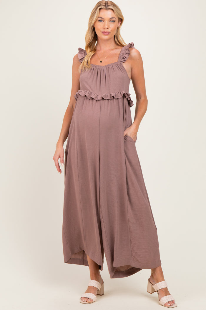 woman wearing a mauve maternity jumpsuit with ruffled straps and pockets, showing her baby bump