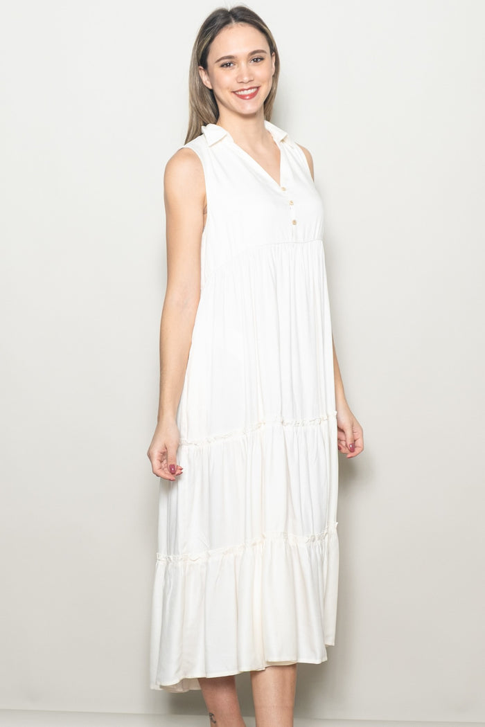 woman wearing a sleeveless white tiered midi dress with a collar and buttons