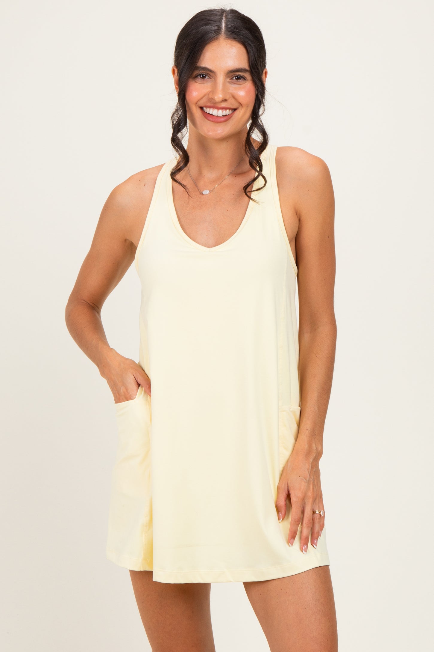 woman wearing a light yellow sleeveless dress with a v-neck and pockets