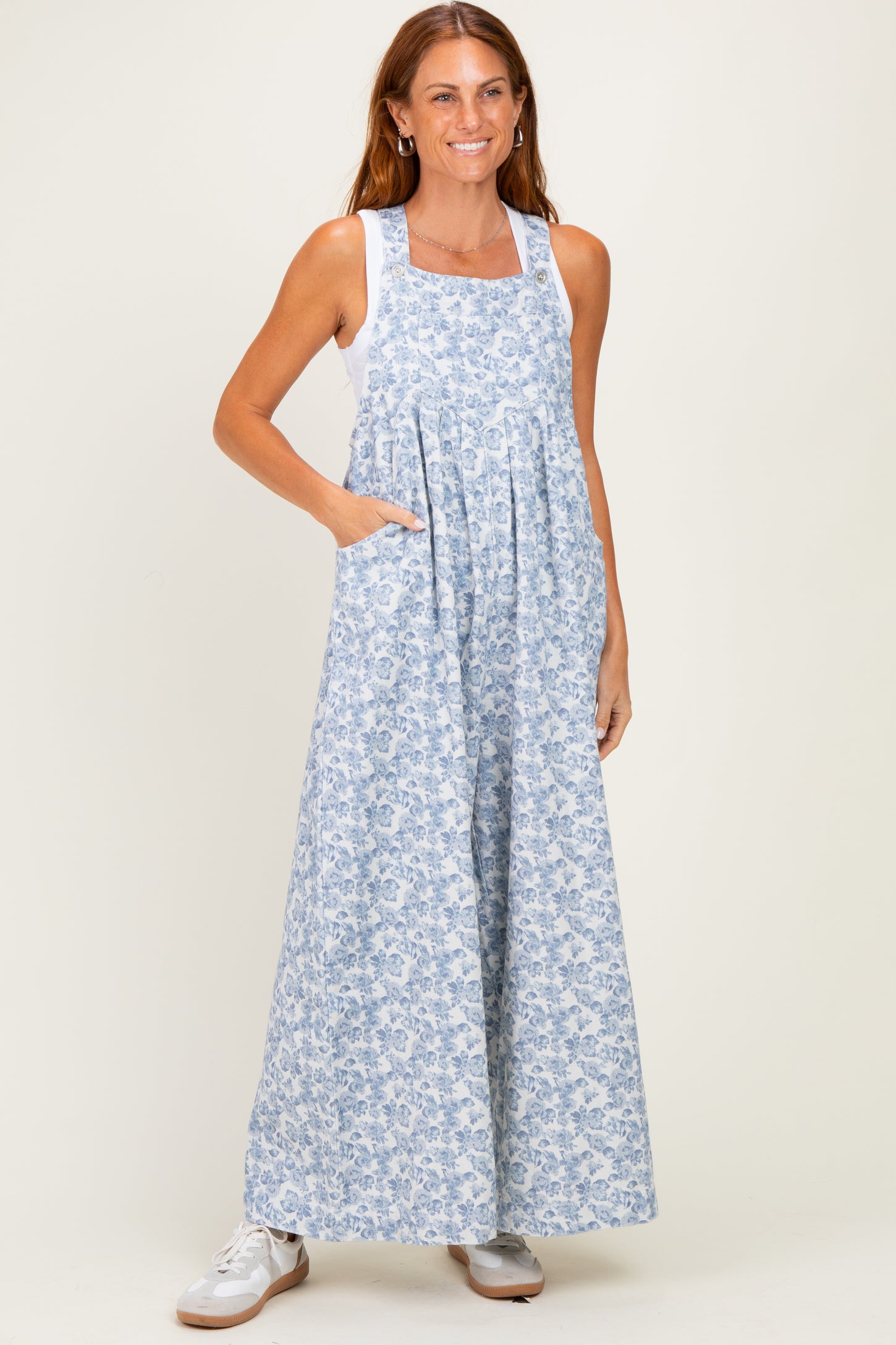 woman wearing a light blue floral maxi dress with pockets and a white tank top underneath