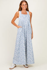 woman wearing a light blue floral maxi dress with pockets and a white tank top underneath
