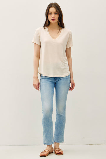 woman wearing a light pink v-neck t-shirt with short sleeves and light blue flared jeans