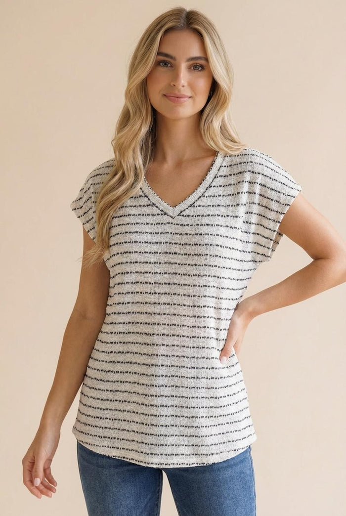 woman wearing a relaxed fit striped v-neck top with short sleeves, styled with blue jeans