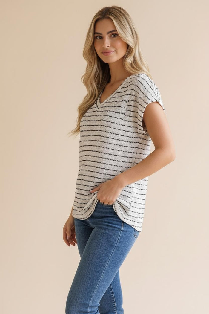 woman wearing a striped short sleeve top with a V-neck and side knot detail, paired with blue jeans