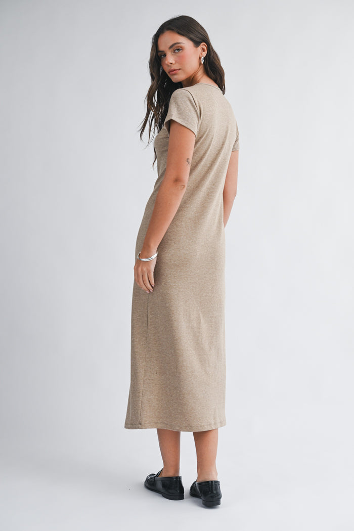 woman wearing a short sleeve tan maxi dress, shown from the back, with her hair down and black shoes
