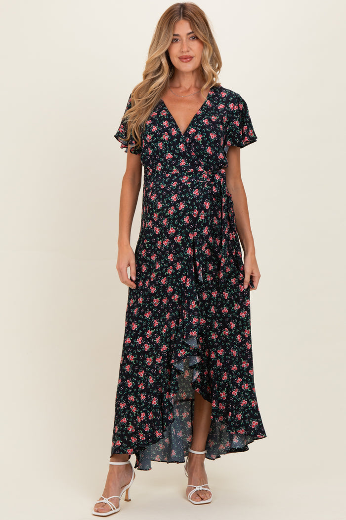 woman wearing a black floral wrap maternity dress with short sleeves and a tiered hem, showcasing her baby bump