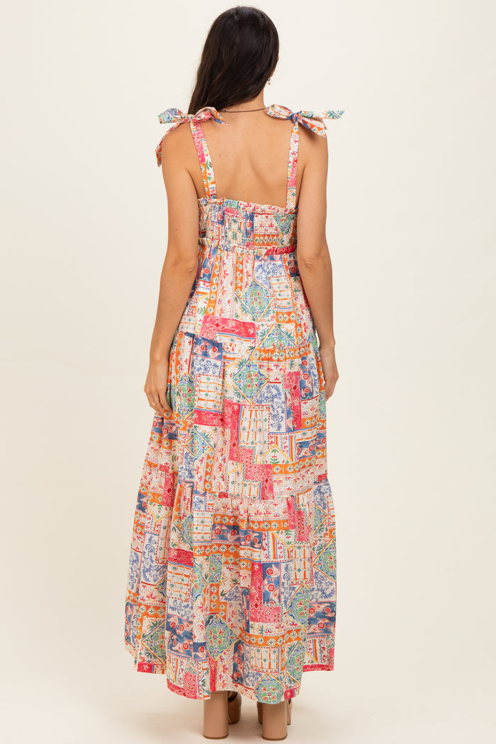 woman wearing a colorful, patterned maxi dress with tie shoulder straps and a smocked back