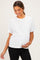 woman wearing a white short sleeve maternity top and holding her baby bump