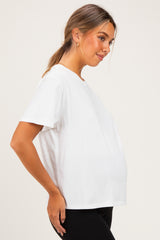woman wearing a white short sleeve maternity top, gently showing her baby bump while smiling