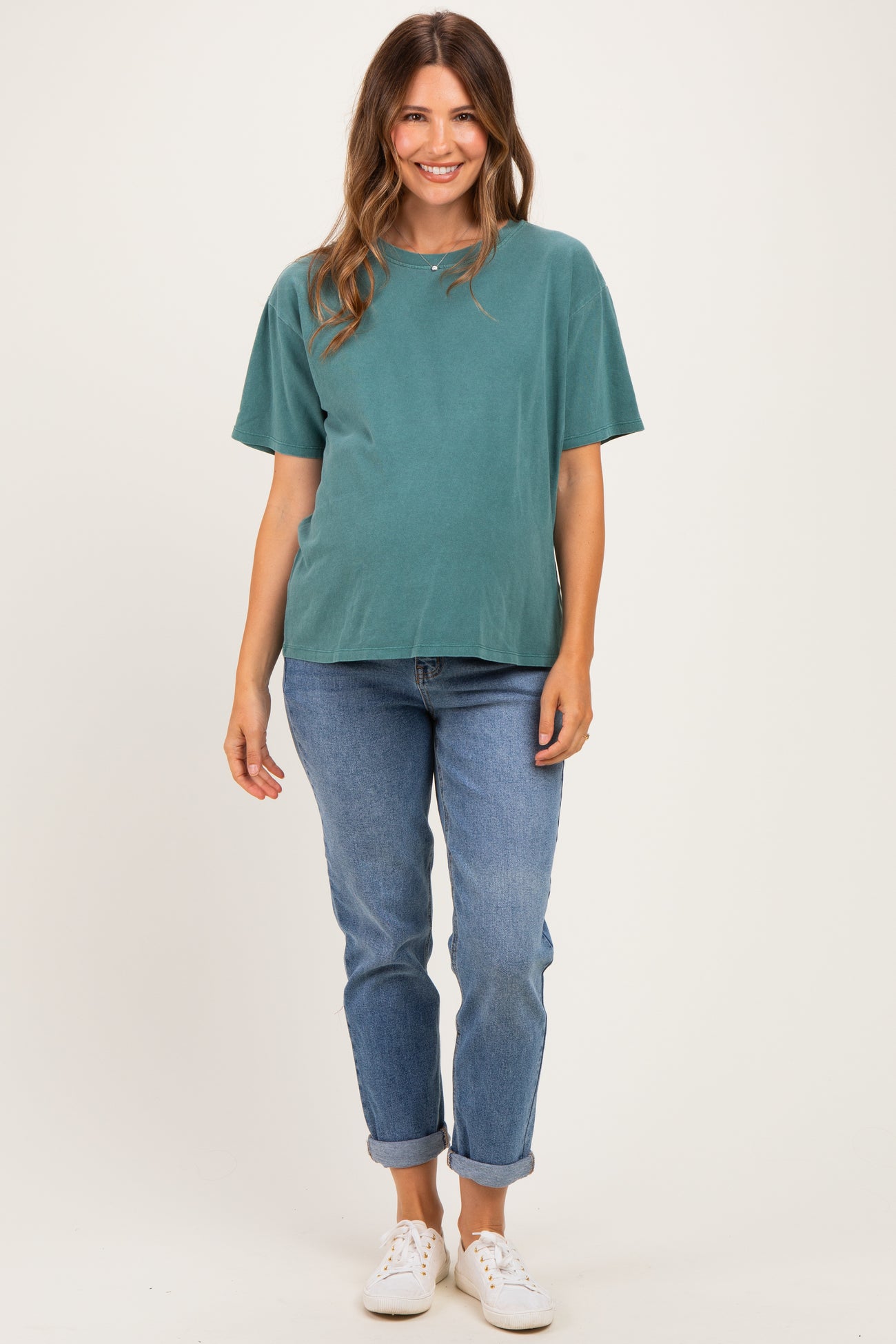 woman wearing a teal maternity t-shirt and blue rolled cuff jeans, showing her baby bump