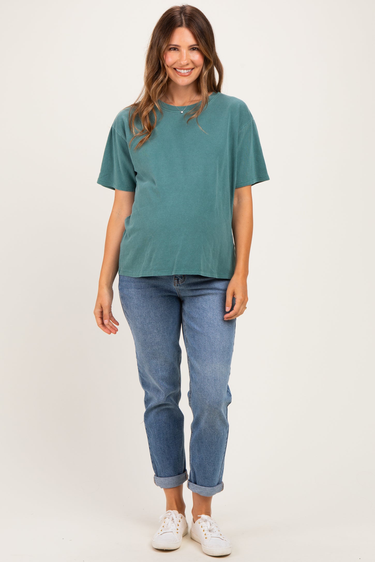 woman wearing a teal maternity t-shirt and blue rolled cuff jeans, showing her baby bump