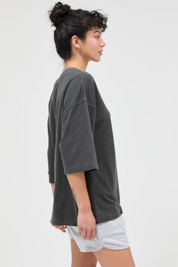 woman wearing a gray oversized short sleeve t-shirt and light gray shorts, side view
