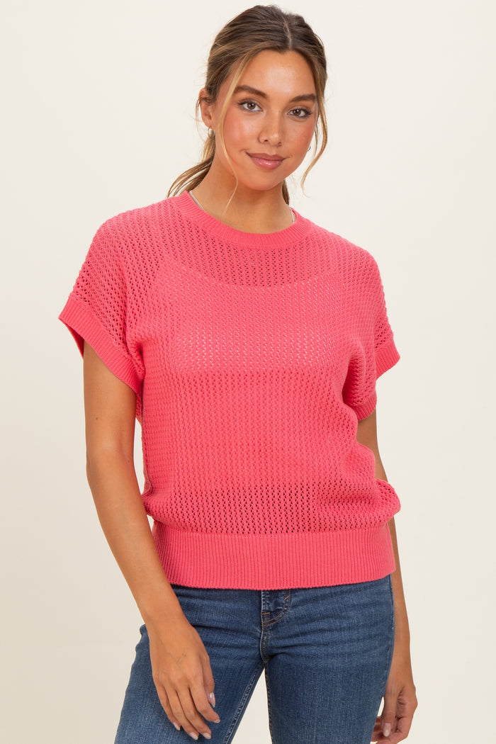 woman wearing a bright pink short sleeve knit sweater with a relaxed fit and a wide crew neckline, paired with denim jeans