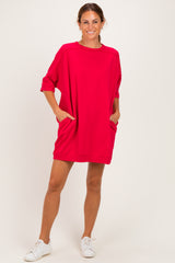 woman wearing a loose-fitting vibrant red short dress with pockets and three-quarter sleeves, paired with white sneakers