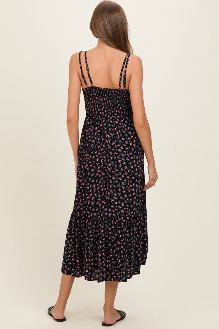 woman wearing a black floral maternity maxi dress with a smocked bodice and tiered ruffle hem, showing her back