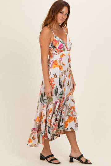 woman wearing a floral midi dress with spaghetti straps and a layered hem, standing sideways with one hand on her hip