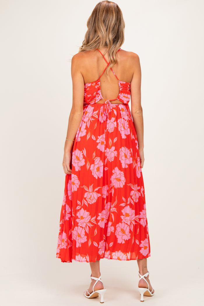 woman wearing a red floral midi maternity dress with a tie back and pleated skirt, showing a baby bump