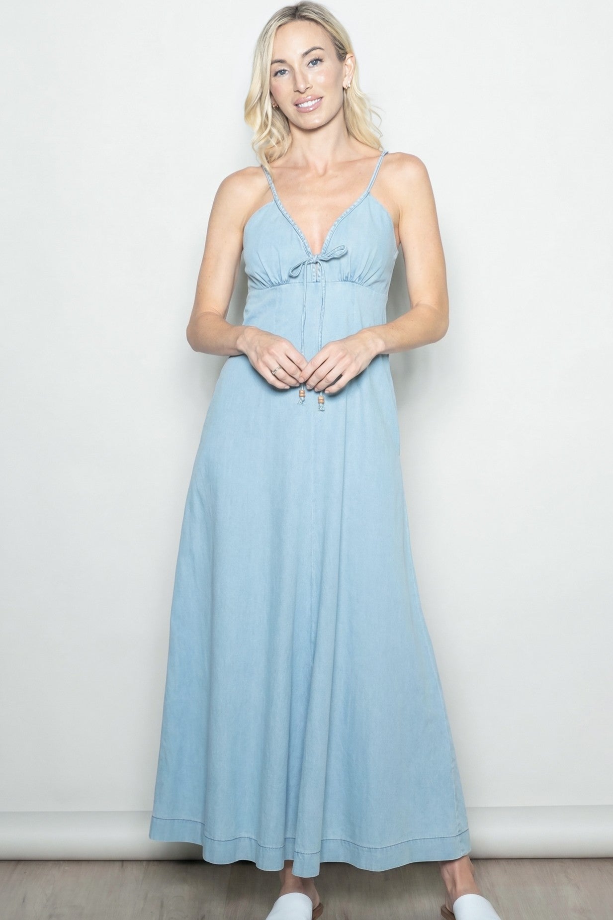 woman wearing a light blue maxi dress with adjustable straps and a tie front detail