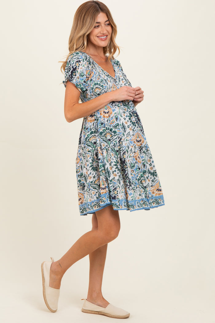 woman wearing a floral print maternity dress with short sleeves and a v-neck, showing her baby bump