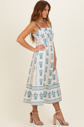 woman wearing a white floral print midi dress with adjustable straps and a cinched waist, standing in profile