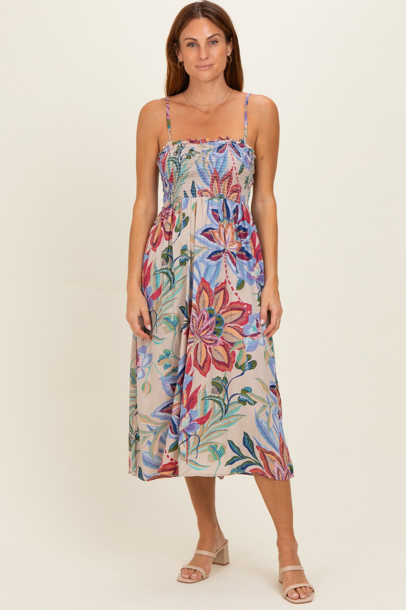 woman wearing a floral print midi dress with a smocked bodice and adjustable spaghetti straps
