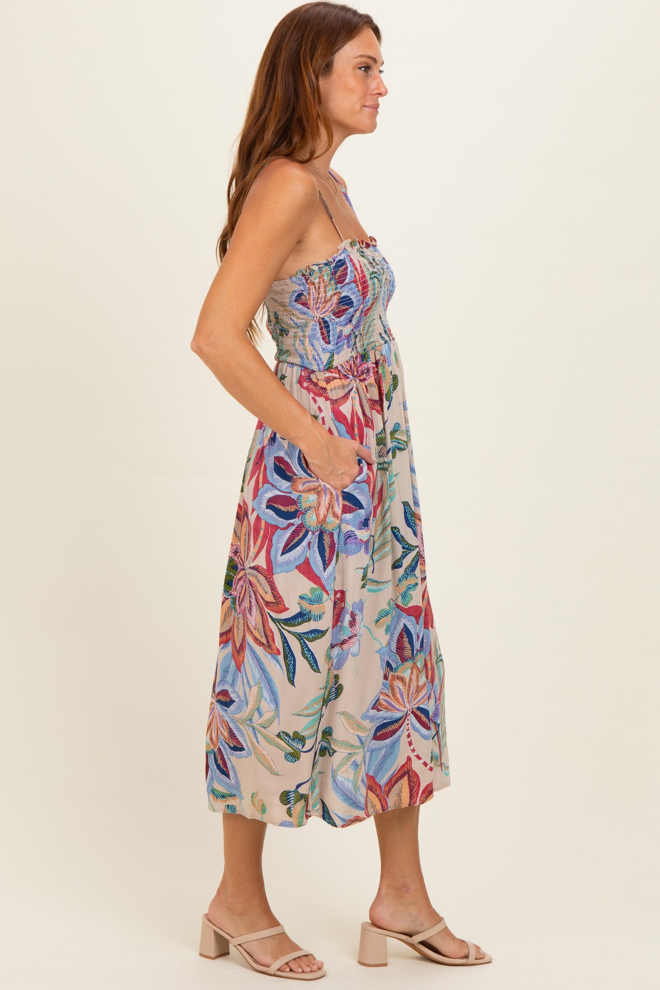 woman wearing a floral print midi dress with smocked bodice and pockets, standing sideways