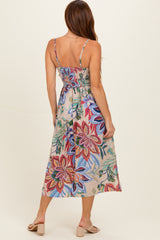 woman wearing a floral midi dress with a fitted bodice and back smocking, featuring colorful flower patterns