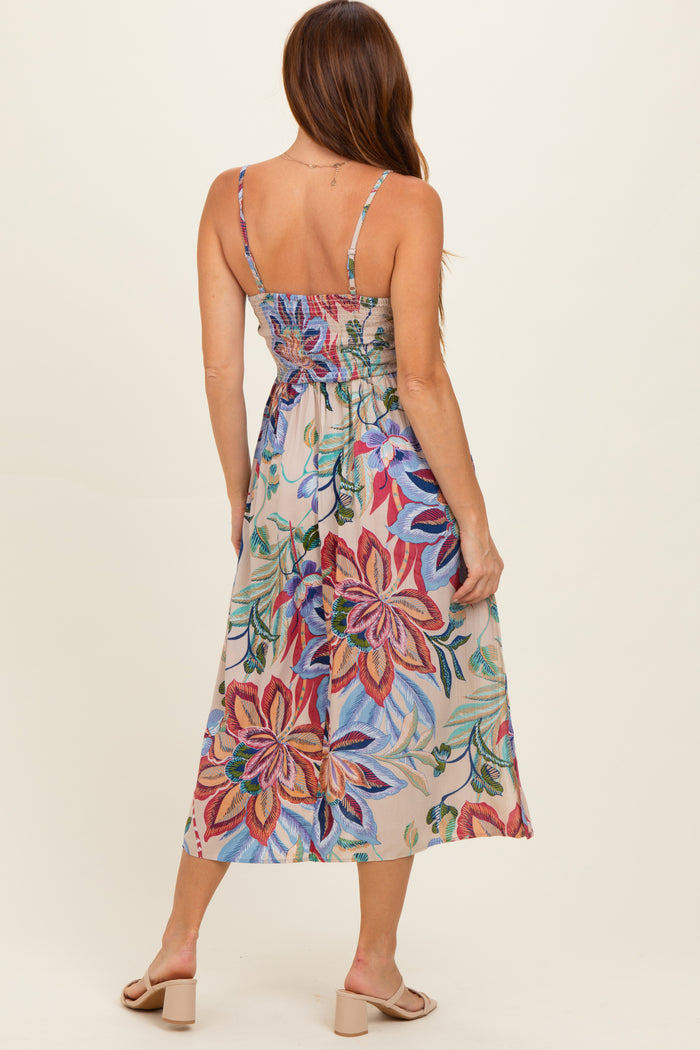 woman wearing a floral midi dress with a fitted bodice and back smocking, featuring colorful flower patterns
