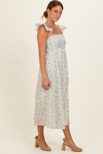 woman wearing a light blue floral maxi dress with ruffle straps and taupe block heel sandals