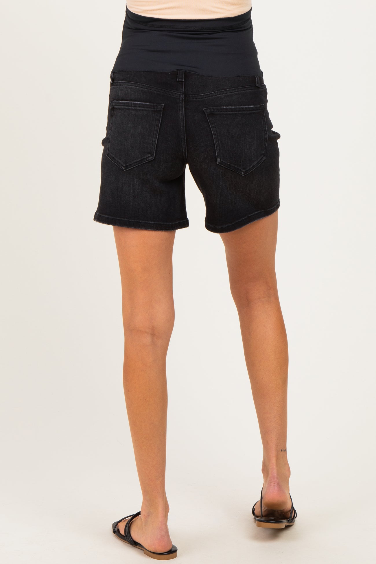 woman wearing black maternity denim shorts with a stretchy waistband, viewed from the back