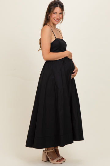 woman wearing a black maternity maxi dress with spaghetti straps and holding her baby bump