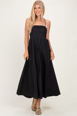 woman wearing a black strapless maxi dress with a flowy skirt and holding it slightly at the waist