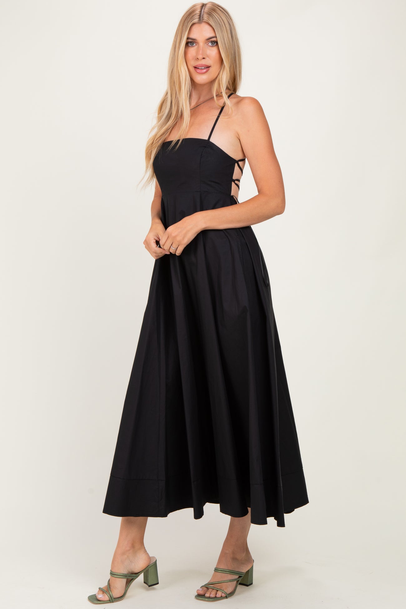woman wearing a black spaghetti strap midi dress with a fitted bodice and flowy skirt