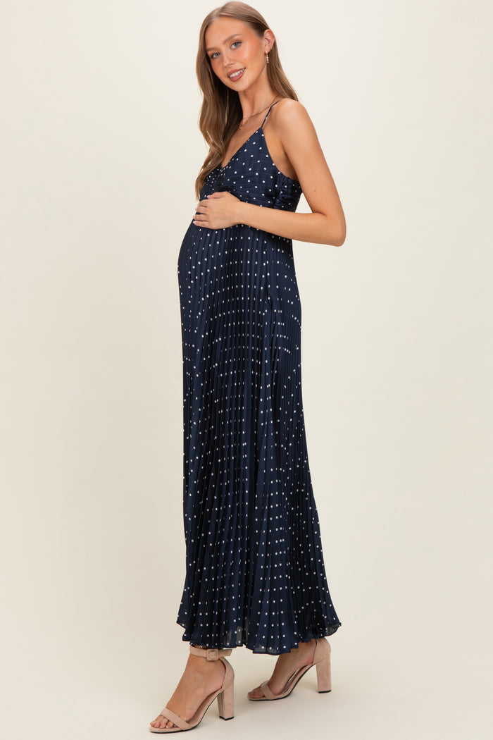 woman wearing a navy blue maternity maxi dress with white polka dots and a visible baby bump