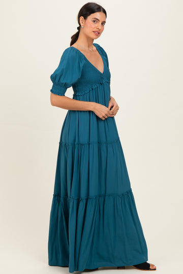 woman wearing a teal maxi dress with puff sleeves and a smocked bodice, posing sideways