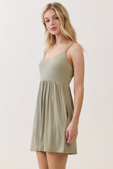 woman wearing a light olive green spaghetti strap dress with a flared skirt