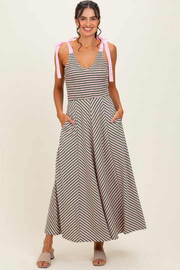 woman wearing a striped maxi dress with a v-neck and pink tie straps, featuring pockets and a fitted bodice