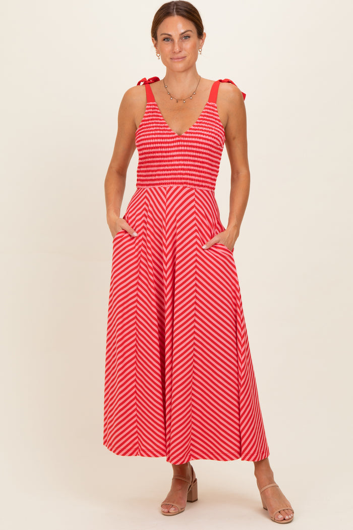 woman wearing a red and white striped maxi dress with a smocked bodice and tie straps, featuring pockets