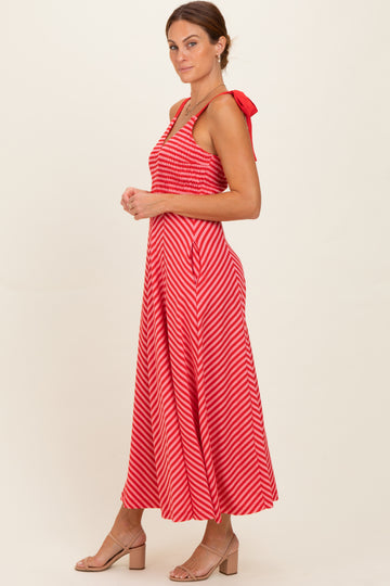 woman wearing a red and white striped maxi dress with a fitted bodice and tie straps, standing sideways